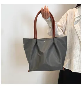 Detail of dark grey nylon tote bag with brown PU leather handles and metal snap button