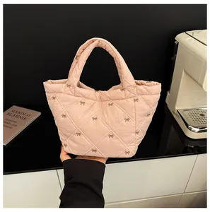 Close-up of pink quilted tote bag with golden bow embroidery and soft puff texture