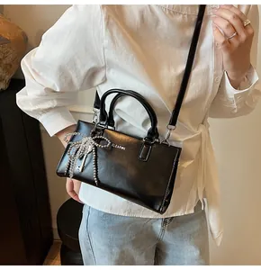 Detail der schwarzen Lederhandtasche mit großer silberner Perlen-Schleife und Logo