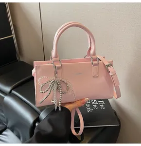 Rosa Handtasche aus Kunstleder mit Clear K-Logo und Perlen-Schleifenanhänger im Detailfoto