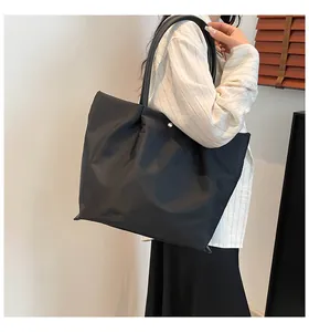 Detailed view of black nylon tote bag showing smooth satin texture and leather straps