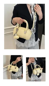 Detail view of cream yellow mini bowling bag with glossy finish and heart charm accessory