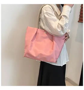 Detail of pink waterproof nylon tote bag with beige handles and golden magnetic snap button