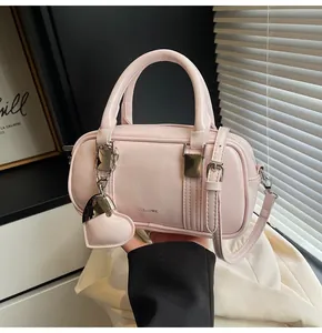 Close-up of pink patent leather boston bag with heart charm and silver hardware