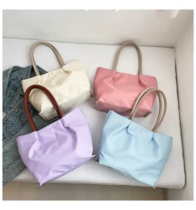 Macro detail of macaron-colored nylon tote bags with pleated design and golden buckle