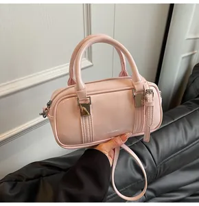Detailed view of pink patent leather pillow bag with double handles and metal hardware