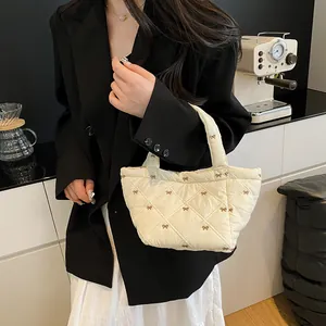 Chic beige quilted puff bucket bag featuring elegant brown bow embroidery and top handle