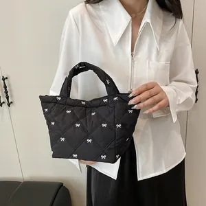 Quilted black bucket bag with white bow embroidery and classic top handle detail