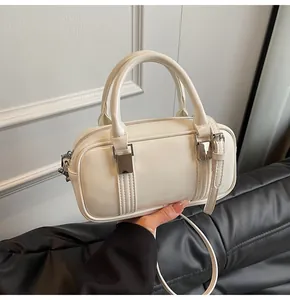 Detail of cream patent leather boston bag featuring silver hardware and glossy finish