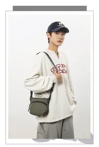 Detailed view of an olive green nylon shoulder bag worn by a model in casual style