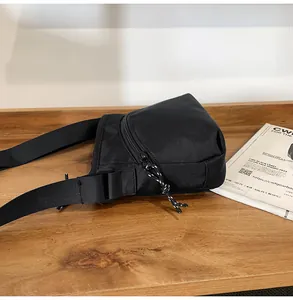 Close-up of black nylon crossbody bag featuring woven zipper pulls and durable strap