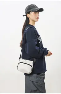 Detailed view of the small white nylon crossbody bag with adjustable black shoulder strap