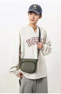 Close-up of olive green nylon crossbody bag showing adjustable strap and front zip pocket