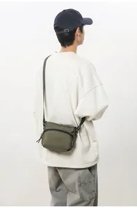 Detail view of military green nylon crossbody bag showing the adjustable strap and zipper