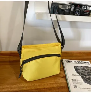 Close-up of bright yellow nylon crossbody bag with black zipper detail on wooden surface