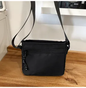 Close-up of black nylon crossbody bag with textured fabric and adjustable strap buckles