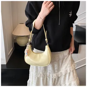 Detail view of cream crescent baguette bag with pearl chain doll pendant charm