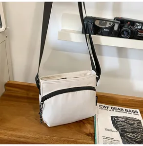 Detailed close-up of a white nylon crossbody bag on a wooden desk with a vintage camera