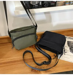 Detail of army green and black nylon crossbody bags on a wooden desk with vintage camera