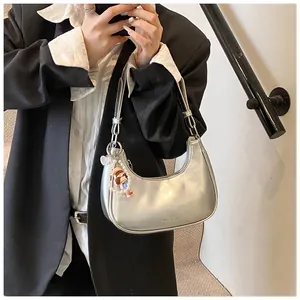 Detail of silver half-moon underarm bag with smooth leather finish and pearl charm