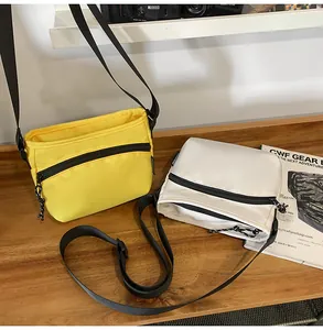Flat lay of nylon crossbody bags in yellow and beige on a wooden desk with a camera