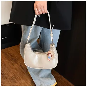 Close-up of pearl white baguette bag with pearl chain and cartoon charm detail