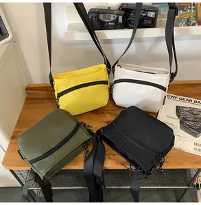 Multi-color nylon crossbody bags displayed on a wooden table with outdoor lifestyle props