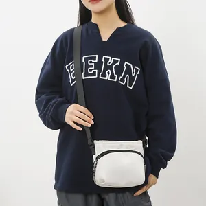 White nylon crossbody bag with wide black adjustable strap and utility zip compartment
