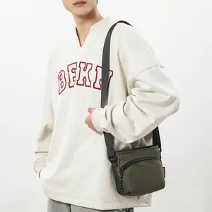 Olive green nylon crossbody bag for men shown on a model with adjustable strap