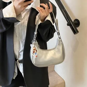 Silver metallic crescent underarm bag with sleek surface and pearl doll charm detail