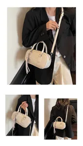 Detail of cream mini bowling bag with embossed UOR JOR logo and tassel charm