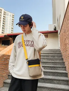Outdoor street style view of a multi-color patchwork nylon crossbody bag with yellow strap