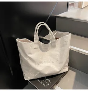 Makroaufnahme weiße Tyvek-Einkaufstasche mit Glanzfalten und geprägtem Logo-Schriftzug