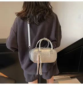 Silver metallic bowling bag shown worn as a crossbody bag on a dark coffee outfit