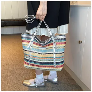 Detail of a large woven tote bag with rainbow stripes and metallic silver handles