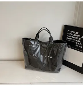 Glänzende schwarze Tyvek-Tragetasche mit TOTE BAG-Schriftzug auf Marmortisch