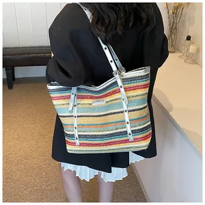 Close-up of a colorful striped woven tote bag with silver metallic straps on a model