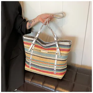 Detail of multi-color striped straw tote bag with silver metallic handles and logo plate