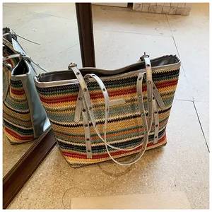 Close-up of a colorful woven straw tote bag with vibrant stripes and silver leather straps
