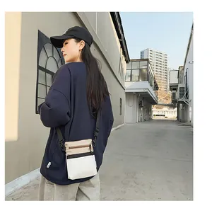 Outdoor shot of a tricolor nylon crossbody bag with khaki, black, and white patchwork details