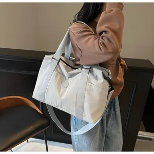 Close-up of light gray travel bag with reinforced handles and adjustable strap detail