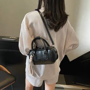 Retro black bowling handbag with textured leather and knot tassel charm worn by model