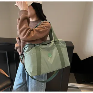 Detailed side view of a large light green travel duffel bag worn by a model in a gym setting