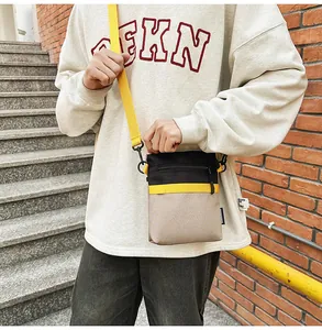Outdoor shot of a color-block nylon crossbody bag showing the adjustable shoulder strap
