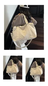 Close-up of beige canvas travel bag with wide handles and adjustable shoulder strap