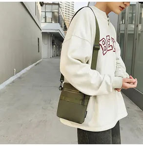 Outdoor shot of army green nylon crossbody bag with zipper pocket and adjustable strap
