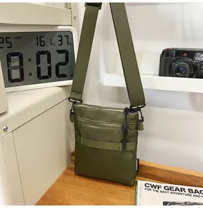 Detail of army green nylon shoulder bag with multiple zippers in a lifestyle EDC setting