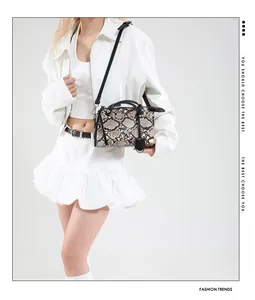 Detail of snake print boston bag featuring black leather handles and adjustable shoulder strap