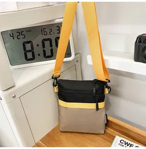 Detail of multi-color nylon messenger bag with yellow strap and zipper closure on wooden desk