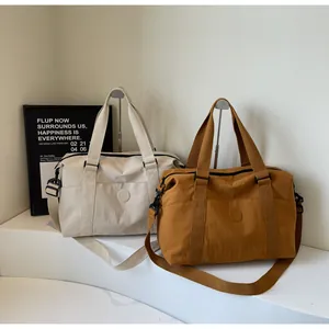 Detail of travel duffle bags in beige and brown with adjustable straps on white steps